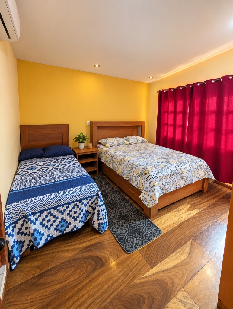 Twin bedroom with red curtains and patterned bedding